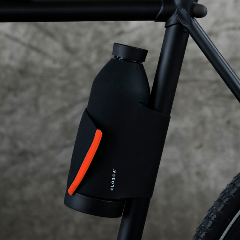 Reusable glass bottle with a soft touch and a patented strap making it hands-free. Double-opening for easy clean in black/coral.