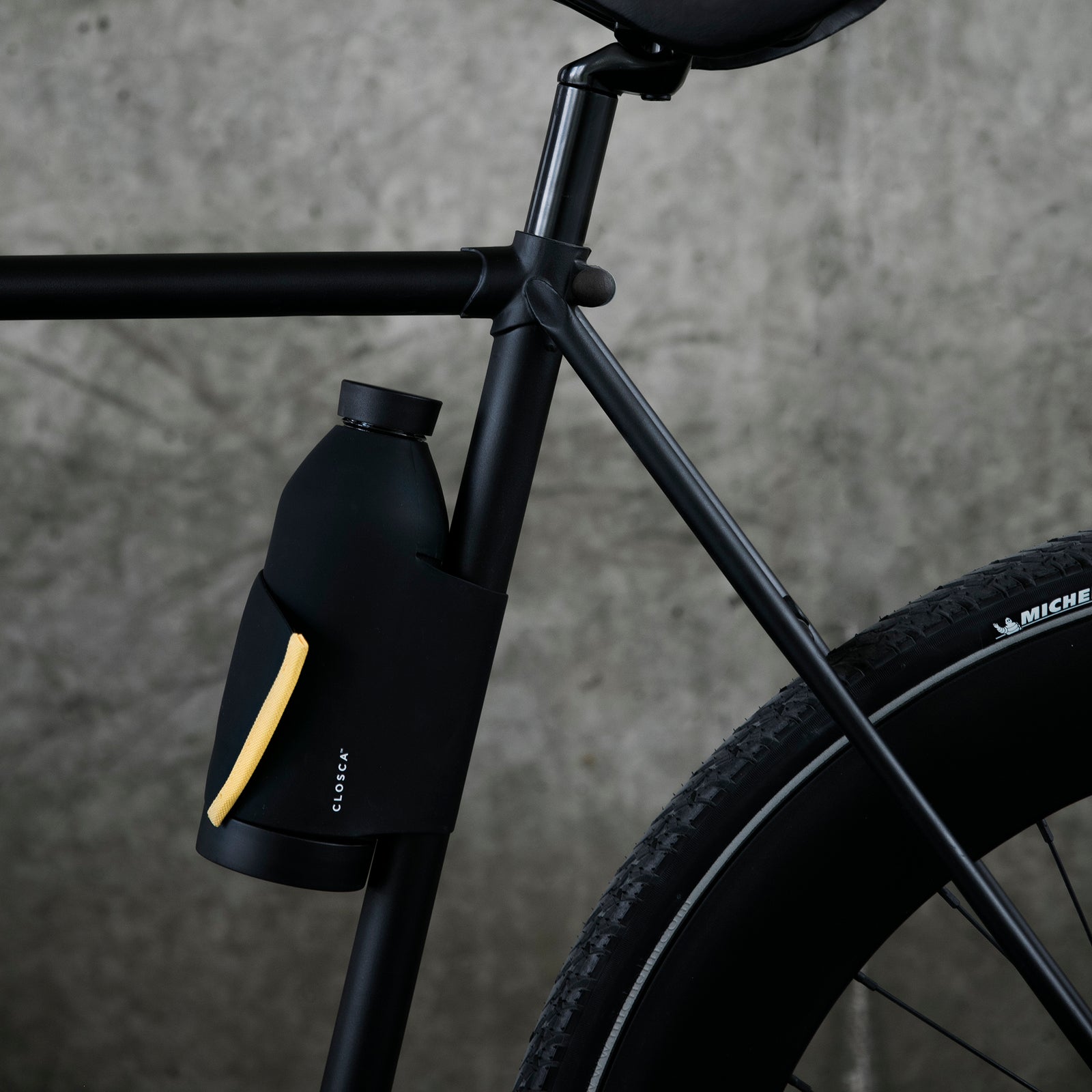 Reusable glass bottle with a soft touch and a patented strap making it hands-free. Double-opening for easy clean in black/mustard.